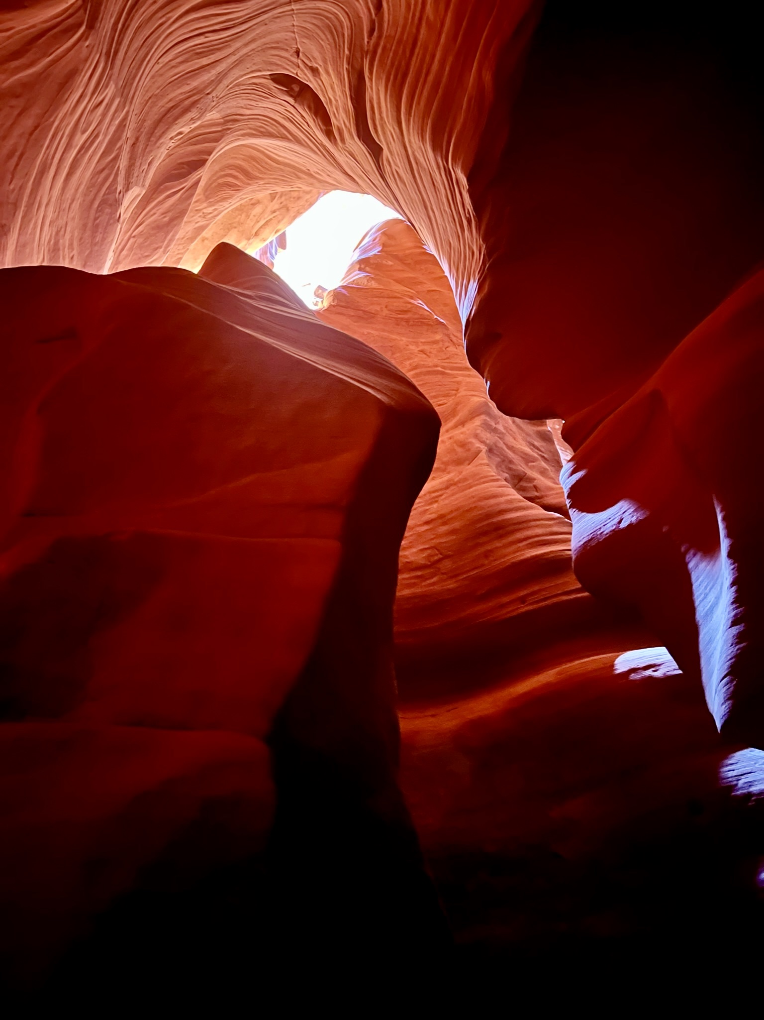 View from inside a red slot canyon looking up with sunlight washing down.