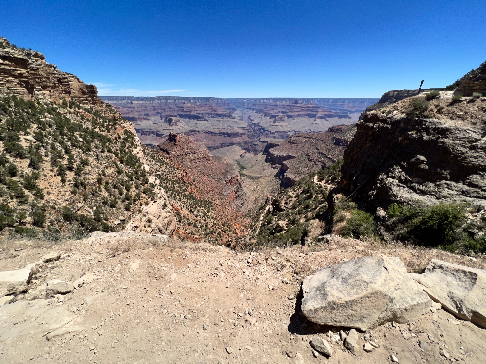 Grand canyon view with red, orange, beige and gray canyon walls, with snaking Colorado river in the distance.