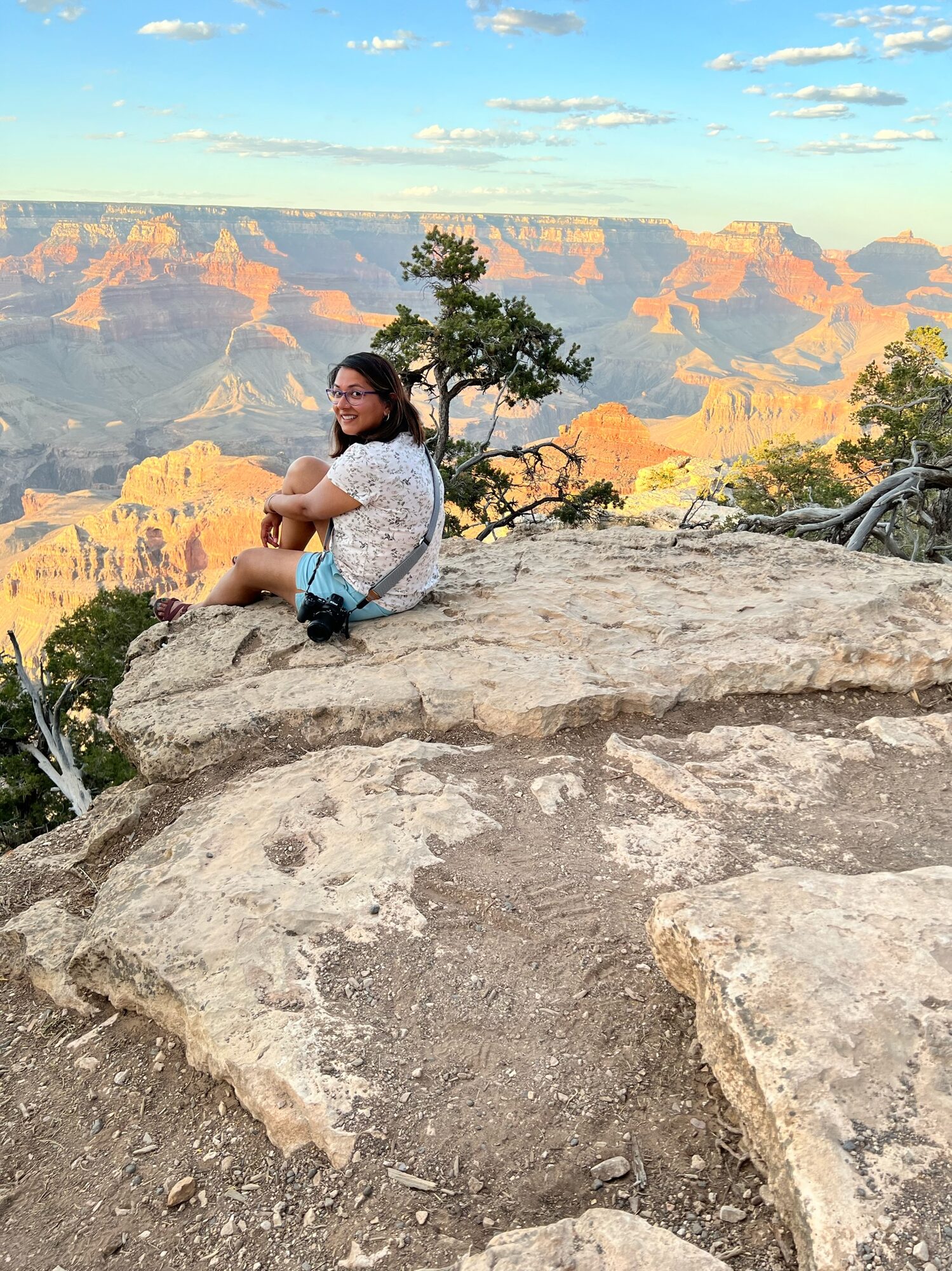 Woman sitting on a rocky ledge above the layered walls of the Grand Canyon