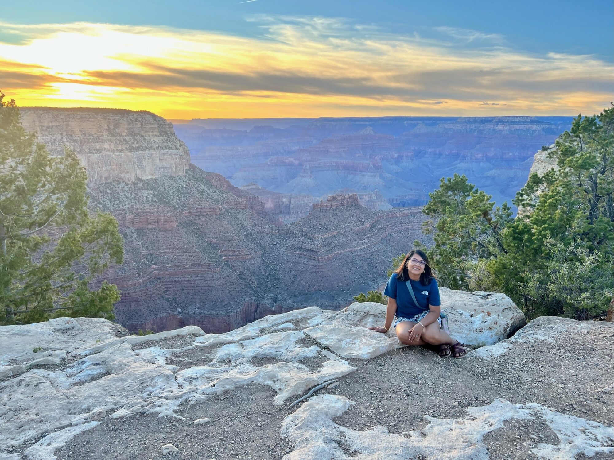 Woman sitting on the South Rim as the sun sets over the Grand Canyon