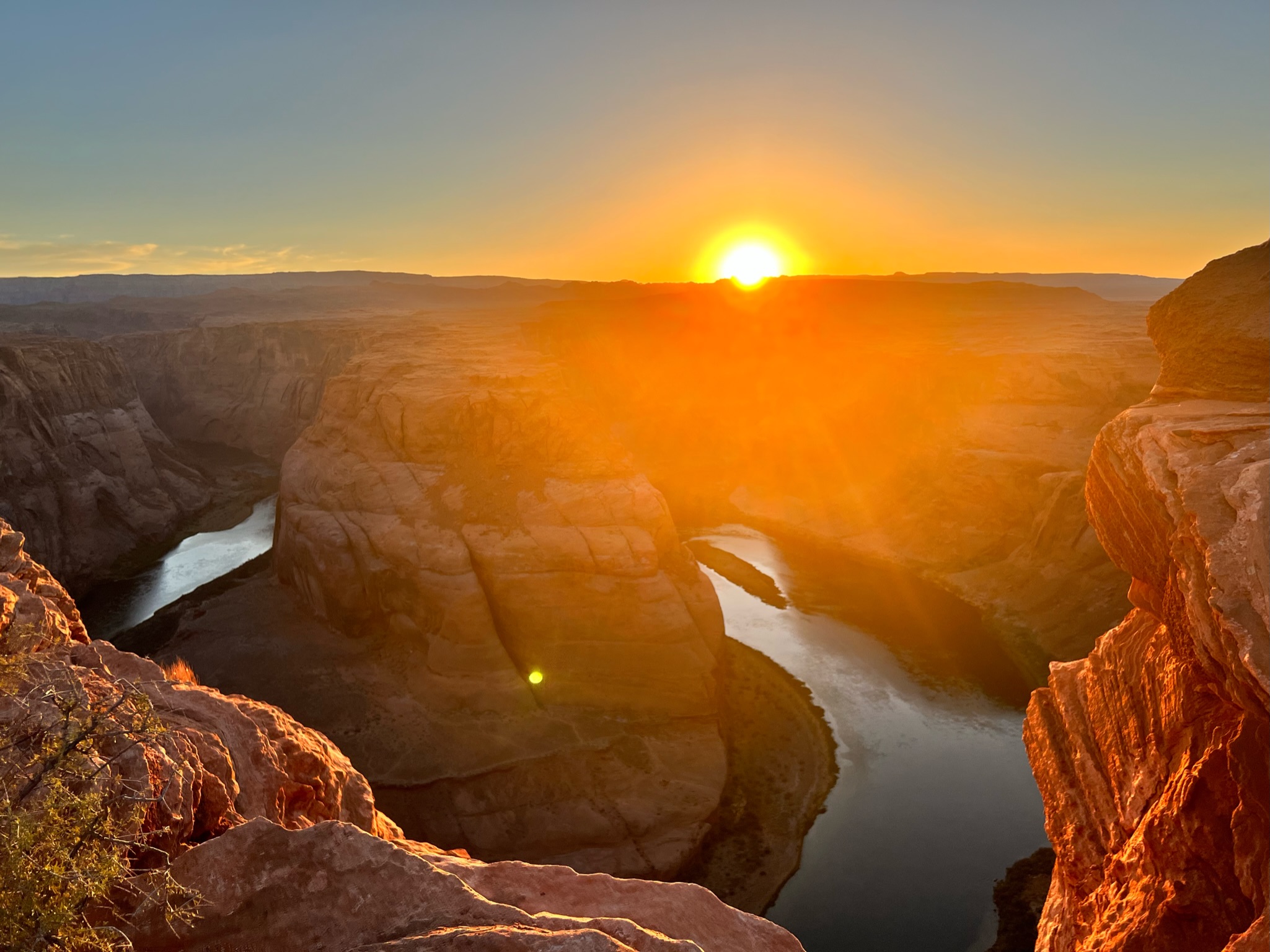 Sunset over the canyons with horse shoe shaped canyon outcrop carved by river at the bottom.