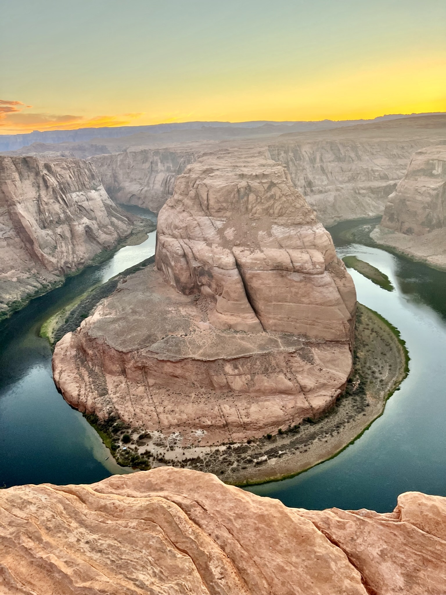 Horse shoe shaped snaking river with red canyon walls and desert landscape all around.