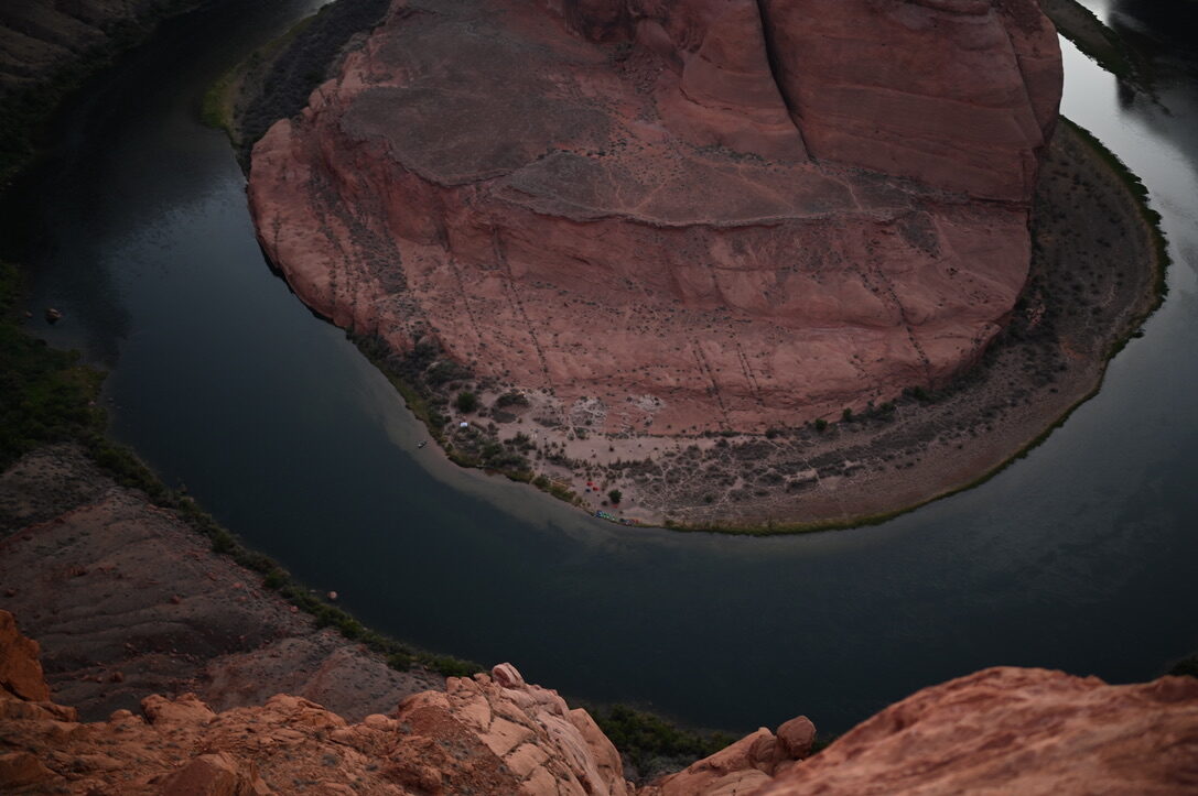 The Colorado River curving around a red rock horseshoe far below