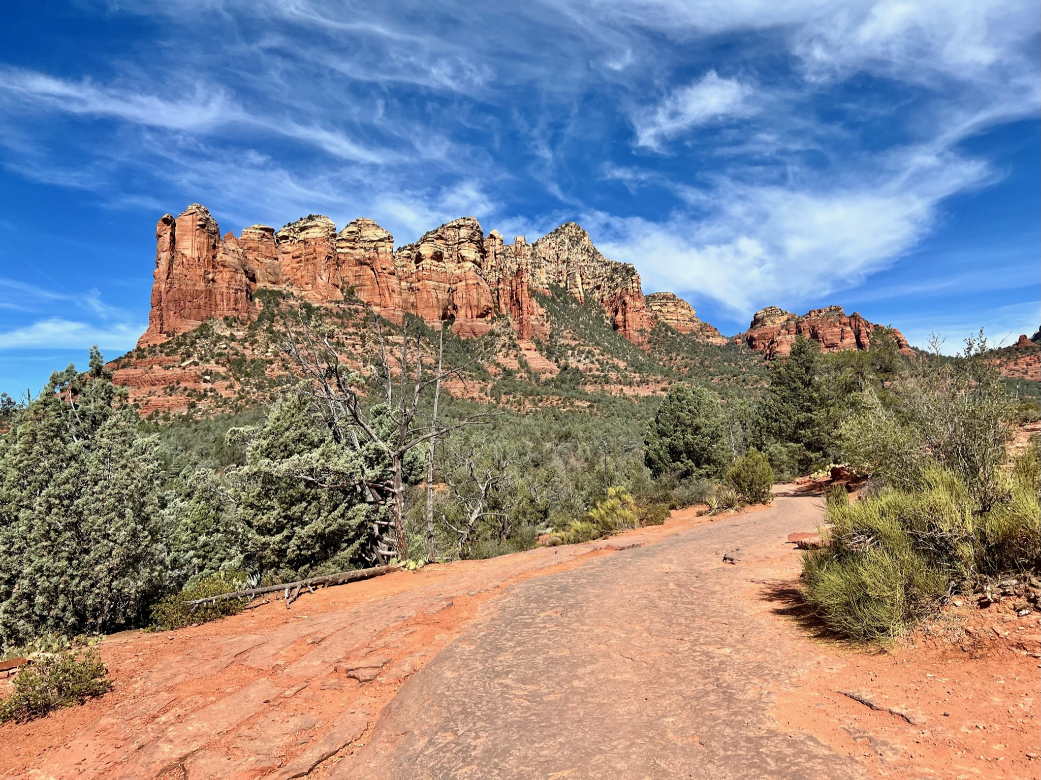 Red mountain peaks with green shrubs and hard trail path in the foreground