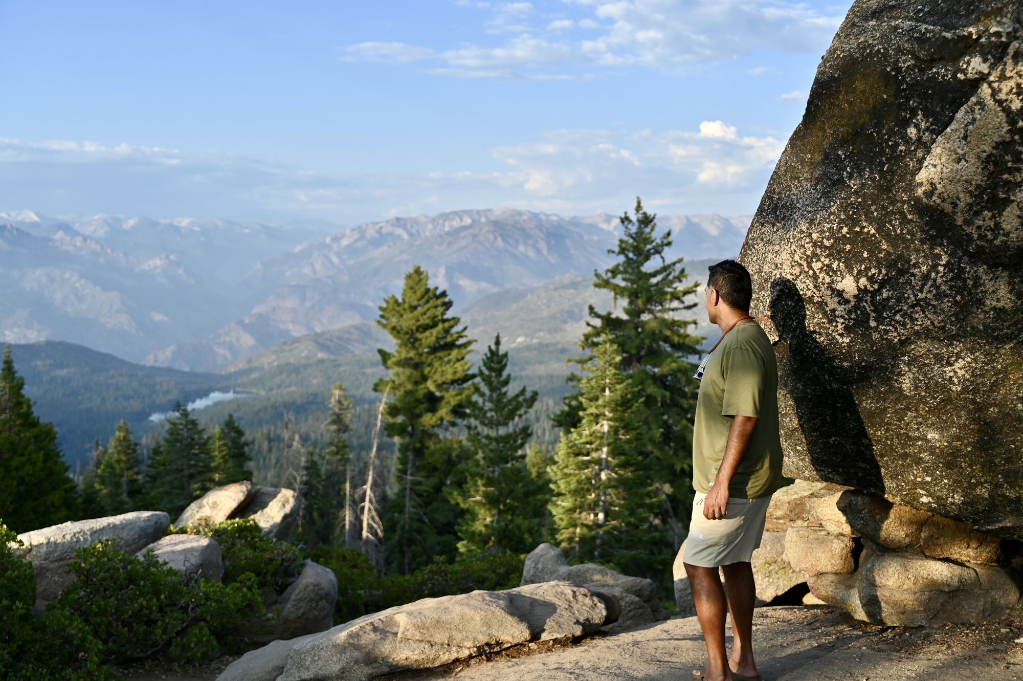 Our son's dad beside a large boulder at Panoramic Point, looking out over forested ridges to distant mountains.