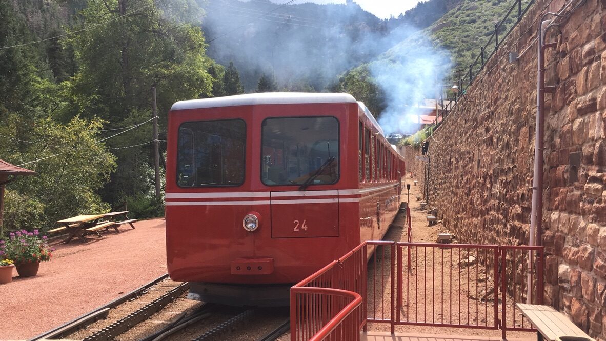 A red cog railway car on the track at the Pikes Peak station