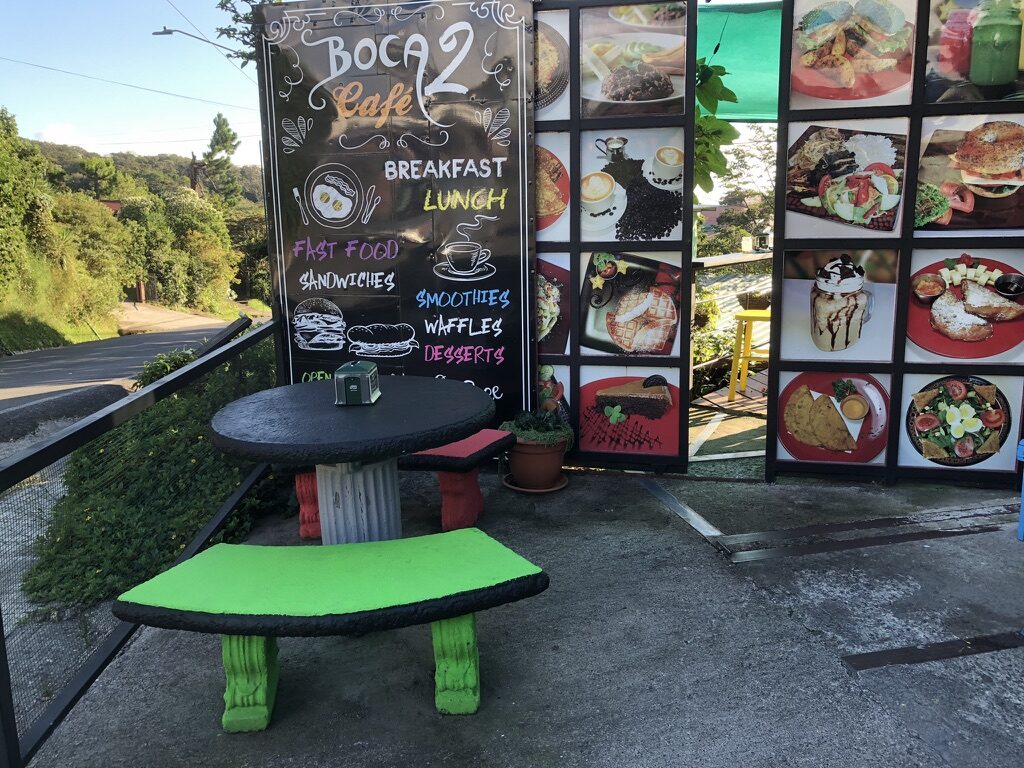A roadside table in front of the Boca 2 cafe’s menu board