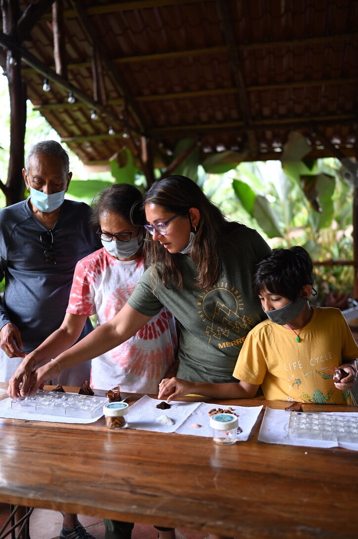 The family at a long table making chocolate in an open-air hut
