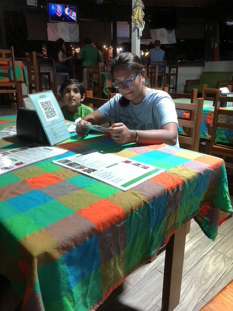 Woman and boy reading menus at a table with a bright patterned tablecloth