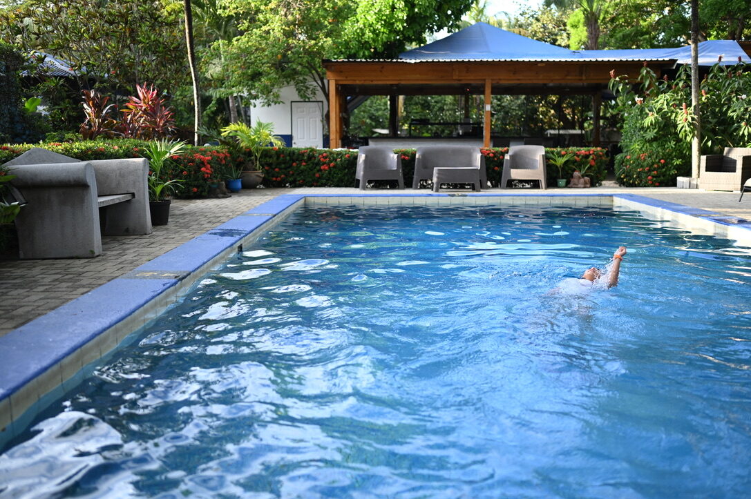 Someone swimming in a hotel pool surrounded by tropical plants
