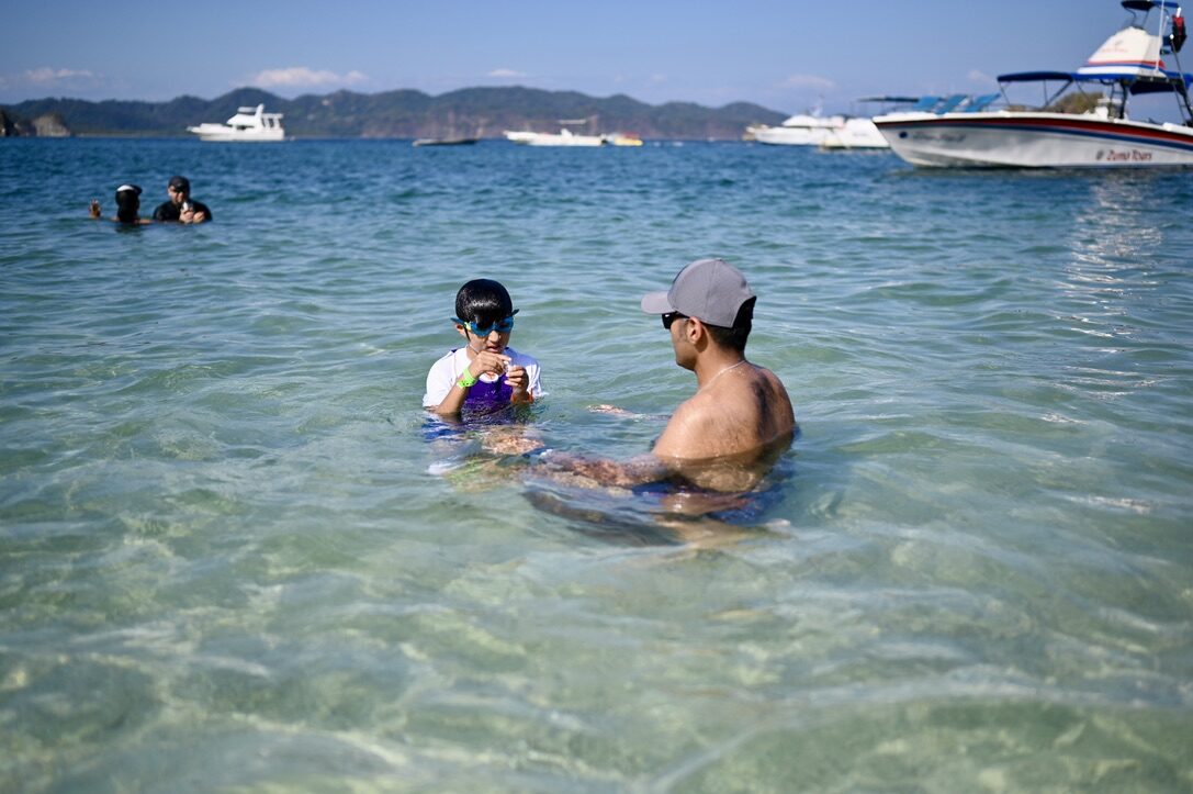 Man and boy sitting in the clear, shallow water