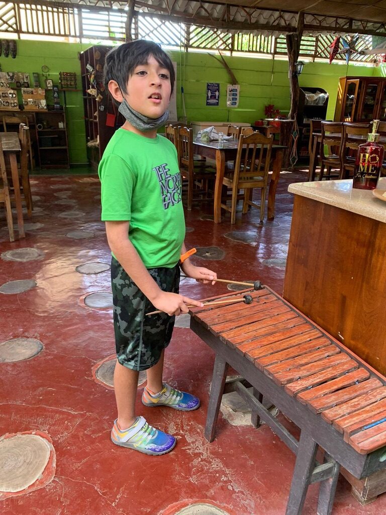 Boy playing a wooden marimba in the tour office