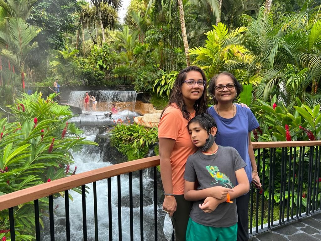 A woman, an older woman and a boy at a railing above a hot spring waterfall