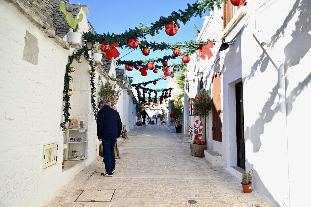 A white street of trulli strung with Christmas decorations