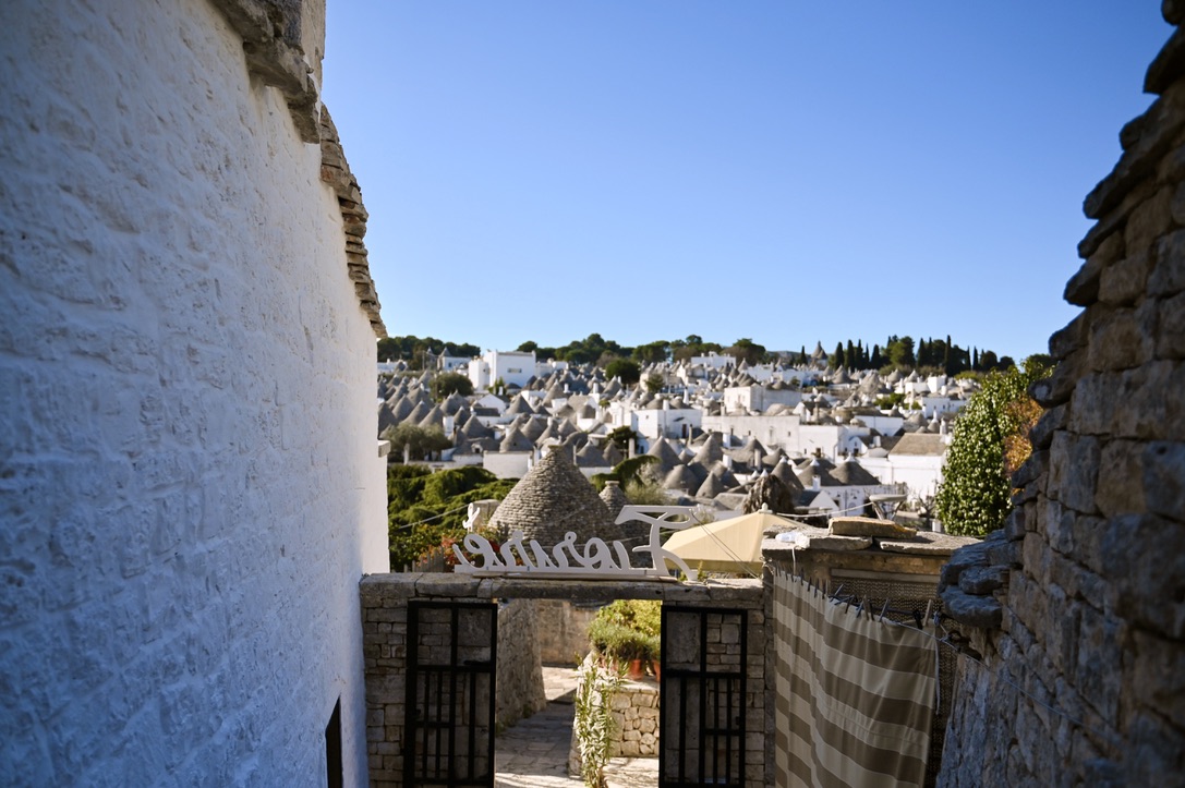 Vista of a village with cone shaped roof tops; the view is framed by stones sides of 2 houses