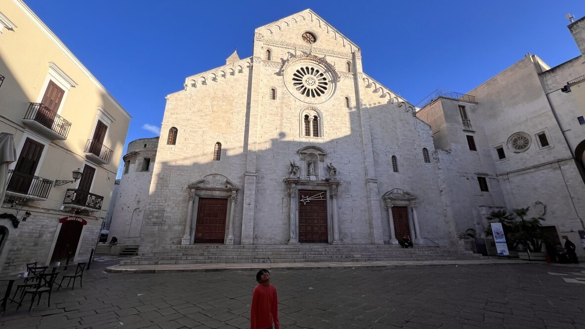 The pale stone facade of Bari Cathedral under a deep blue sky