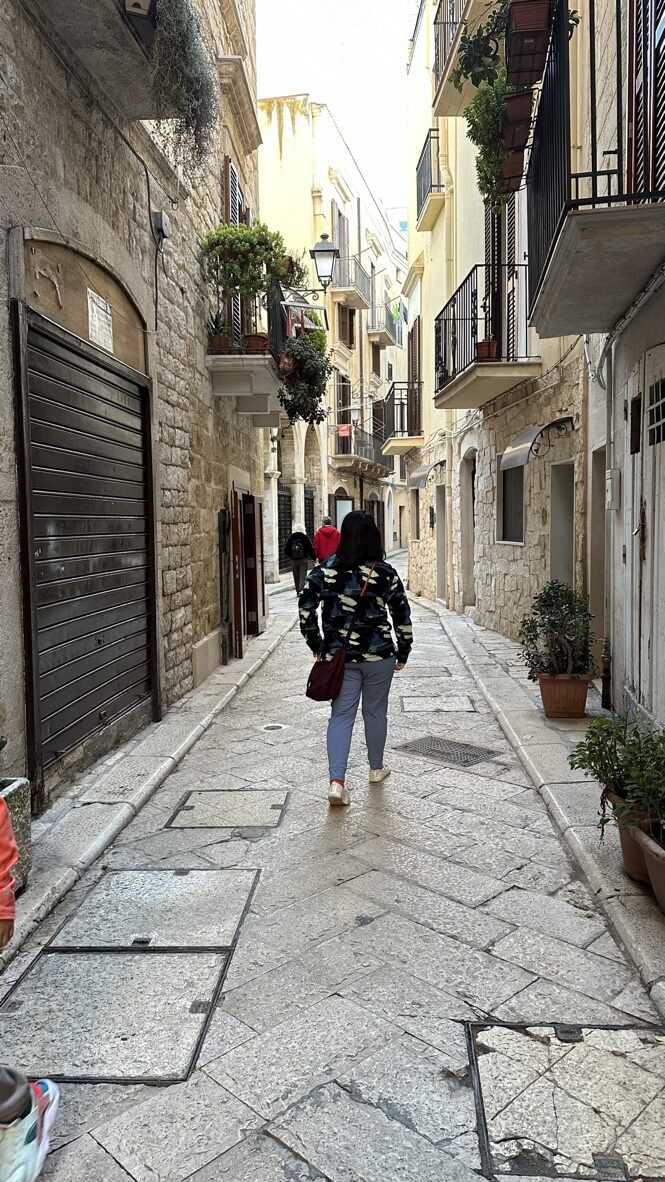 Woman walking down a narrow, stone-paved alley in old town Bari