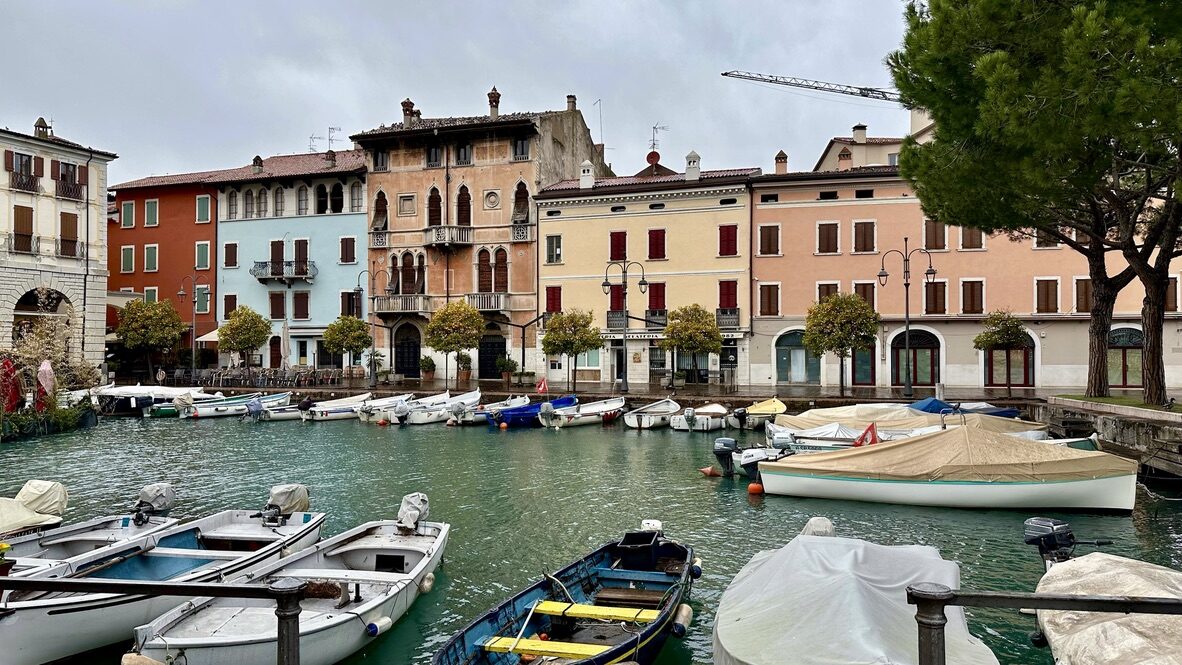 Small boats moored in front of a row of pastel buildings at Desenzano’s old port