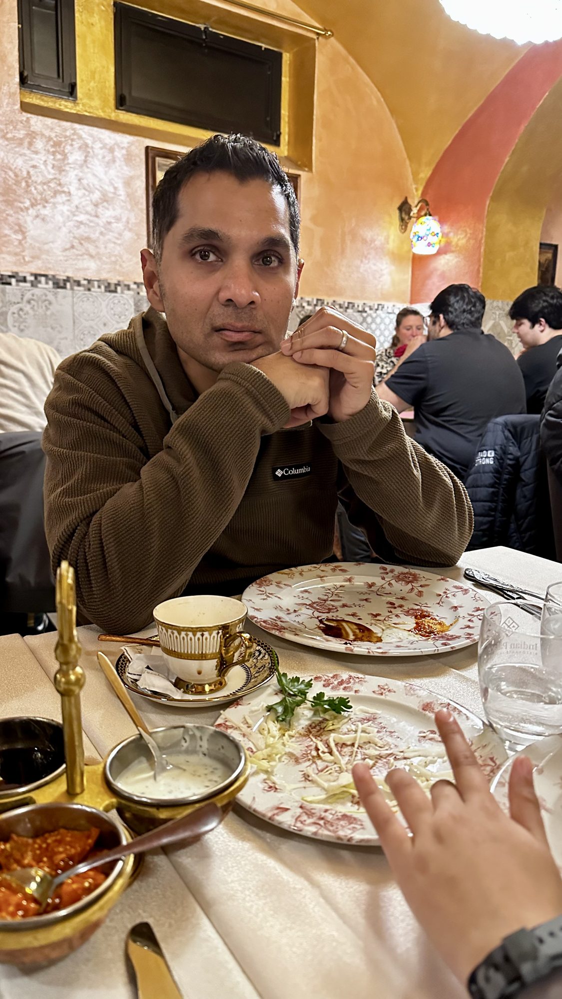 Man at a restaurant table with plates of Indian food