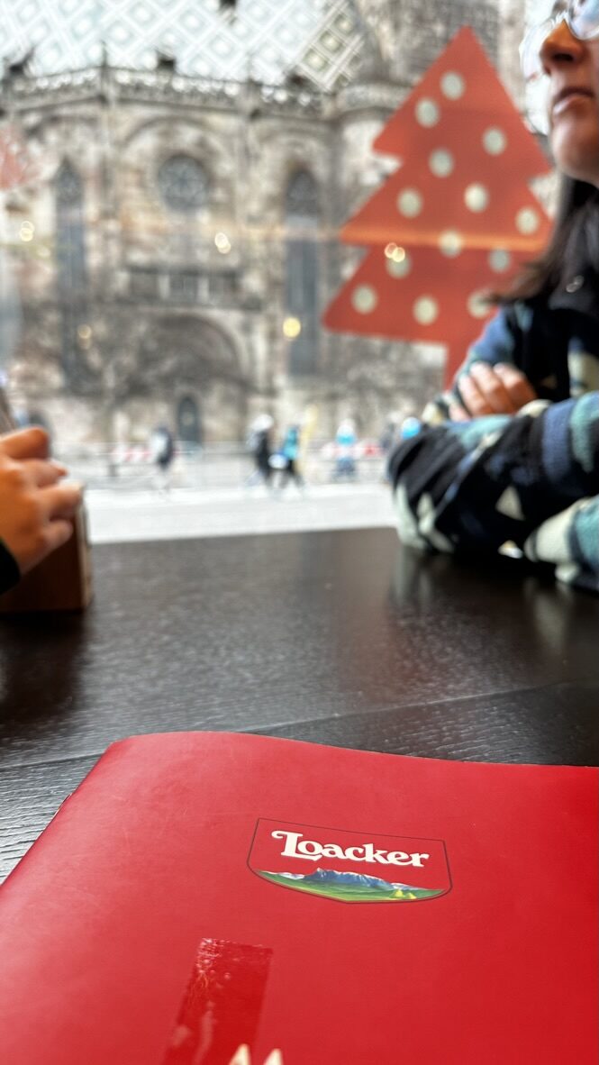 A Loacker menu on the table, with the cathedral blurred through the window