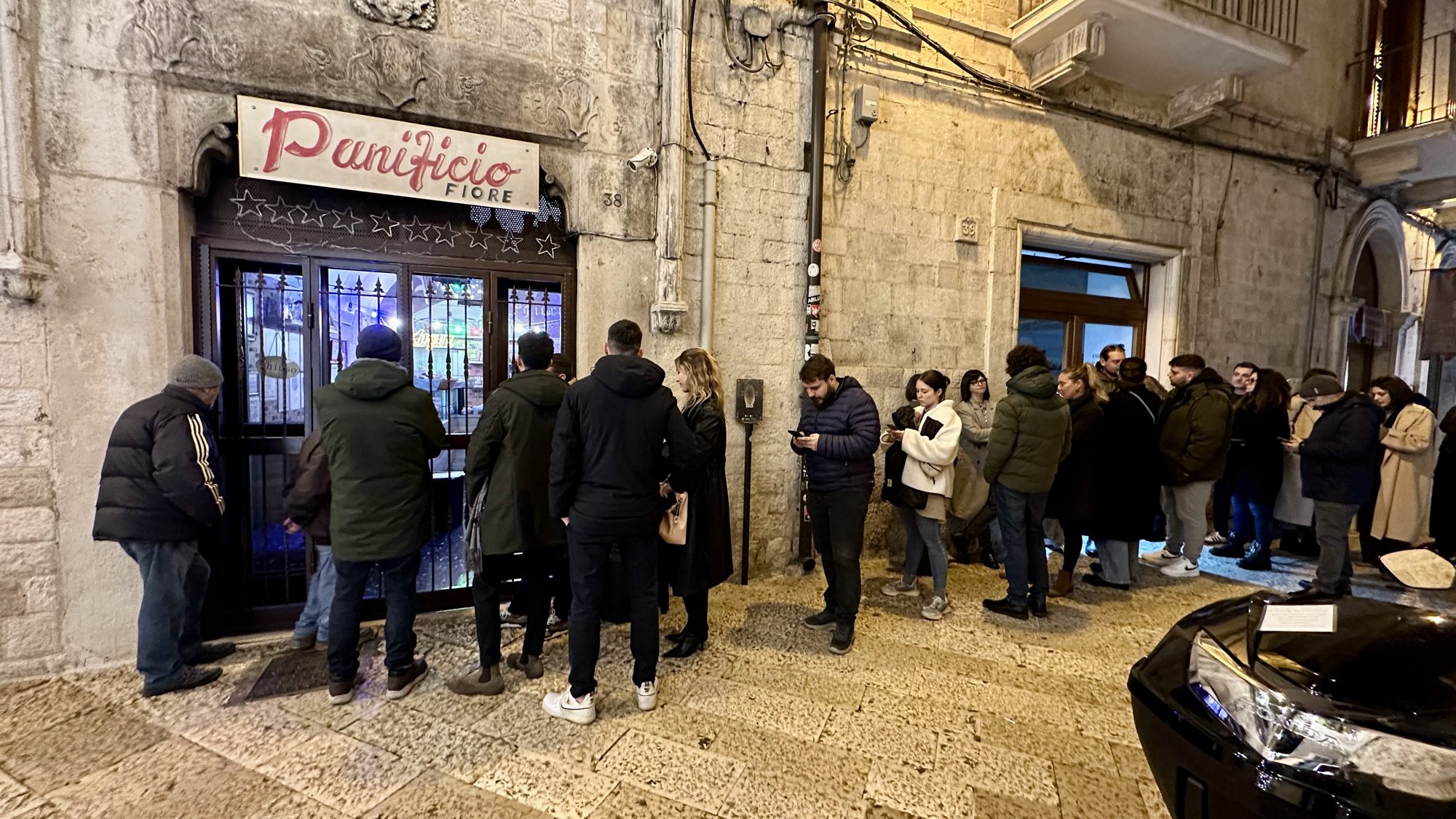 A line of people outside the Panificio Fiore bakery in an old town street