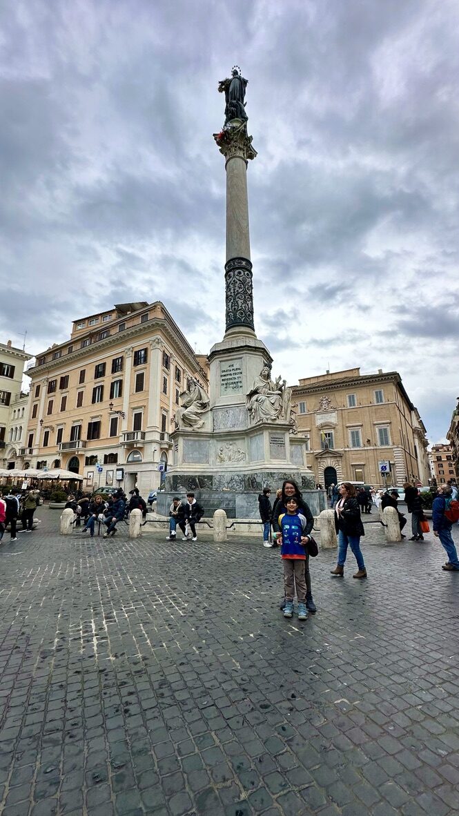 A tall stone column in the square by the Spanish Steps, under a cloudy sky