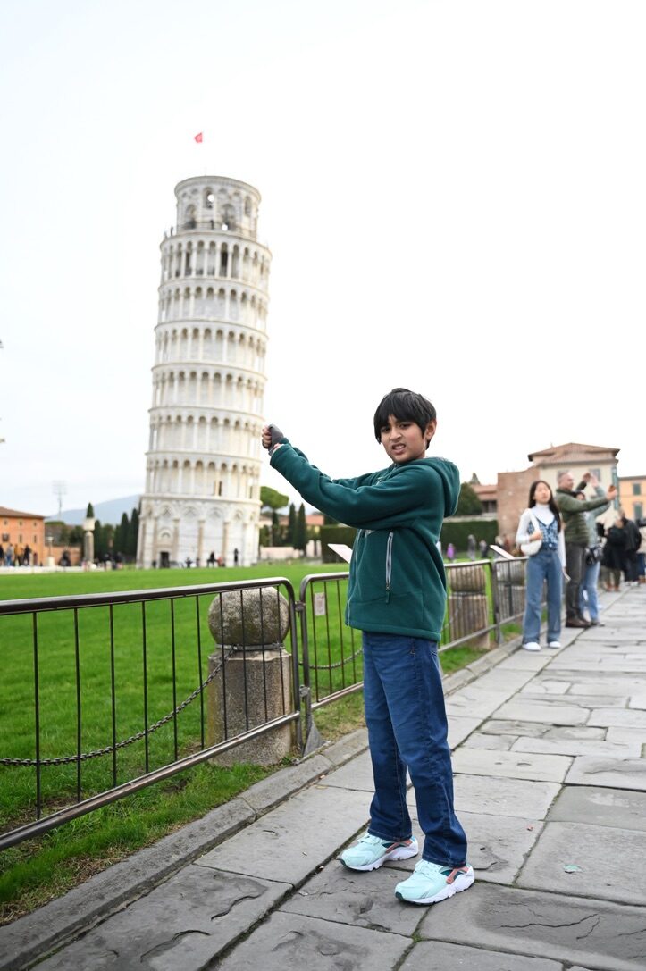 Boy posing as if holding up the Leaning Tower of Pisa