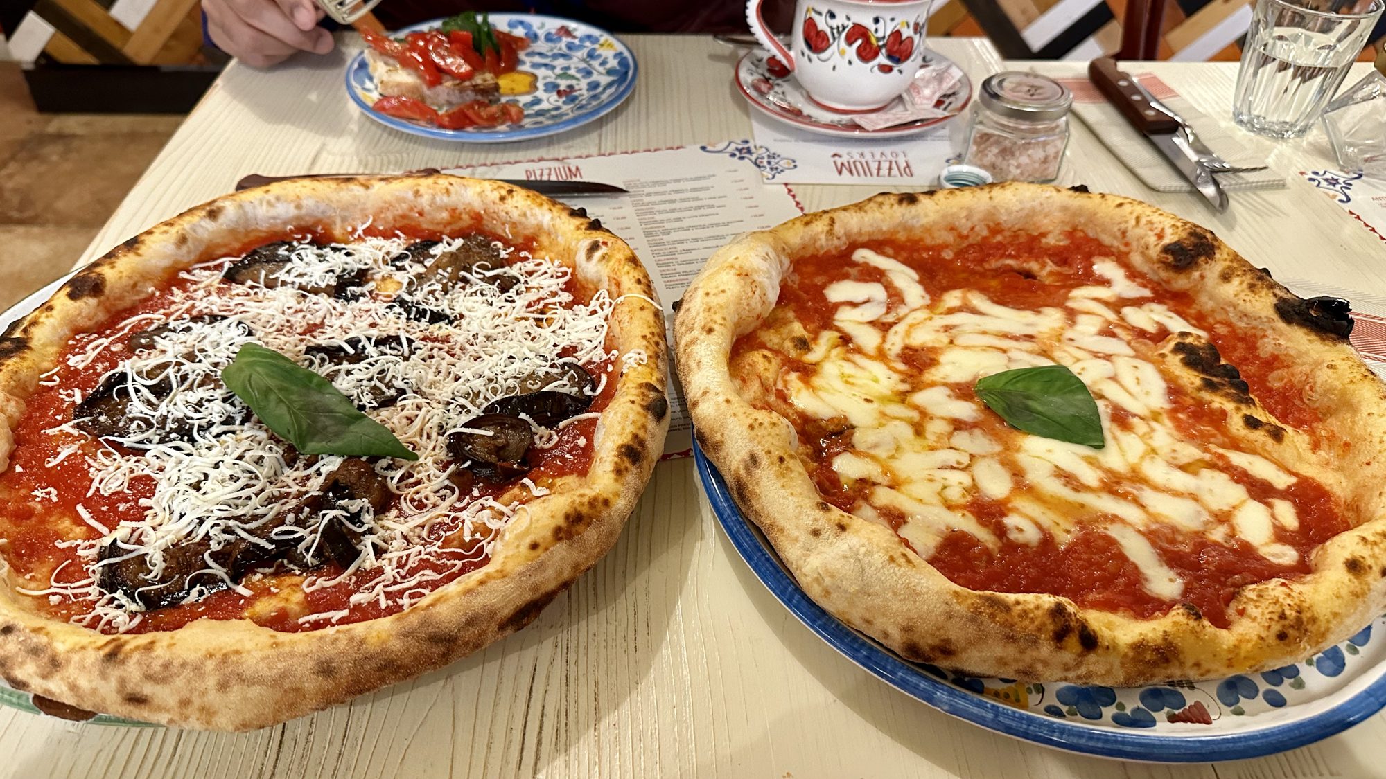 Two Neapolitan pizzas on patterned plates at Pizzium