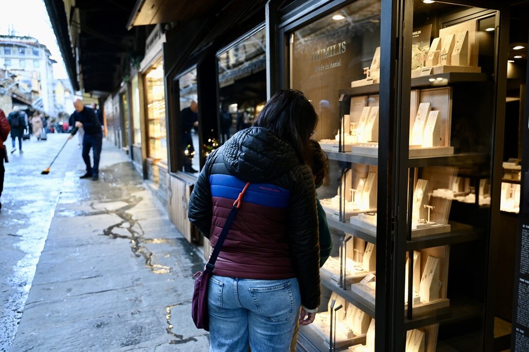Woman looking into a lit jewelry shop window on the Ponte Vecchio