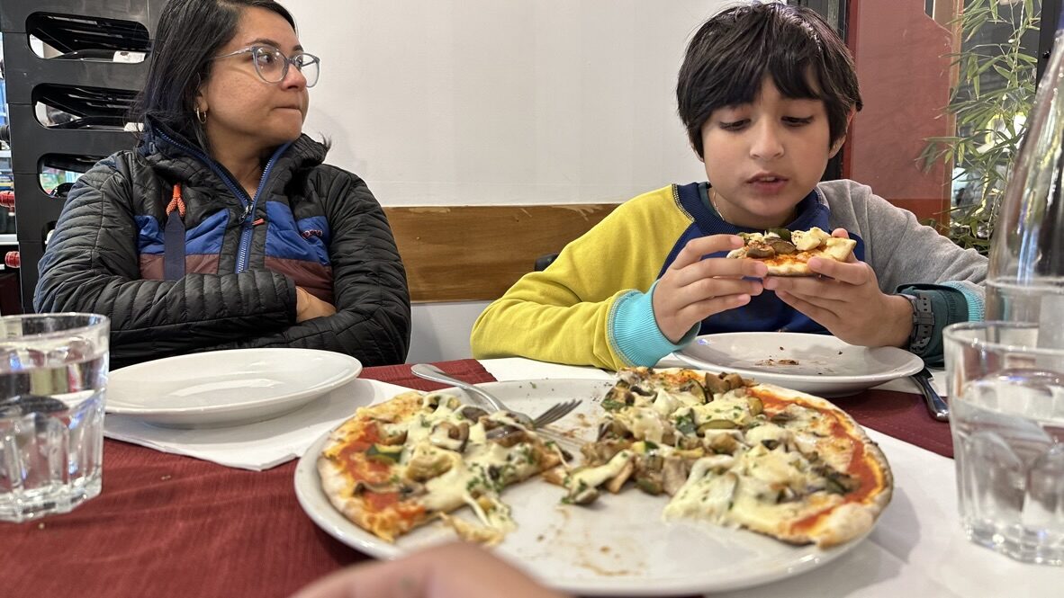 Woman and boy at a table eating pizza