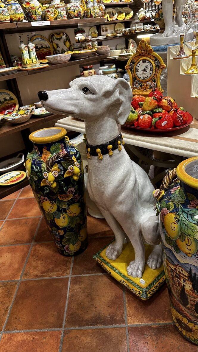 A ceramic dog statue among painted pottery in a souvenir shop