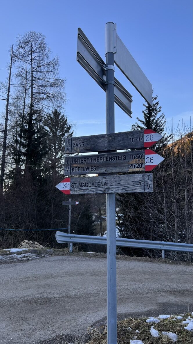 Wooden trail signposts beside the road near Santa Maddalena