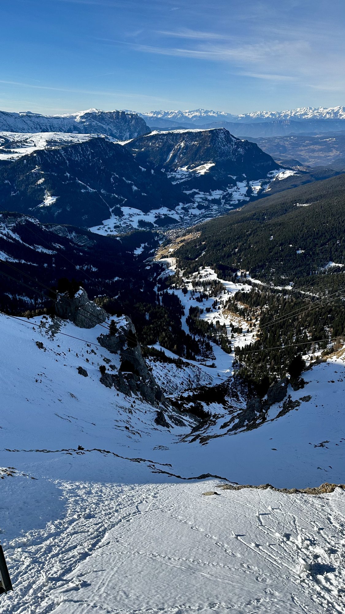 Looking down a snowy slope into a deep valley with mountains beyond