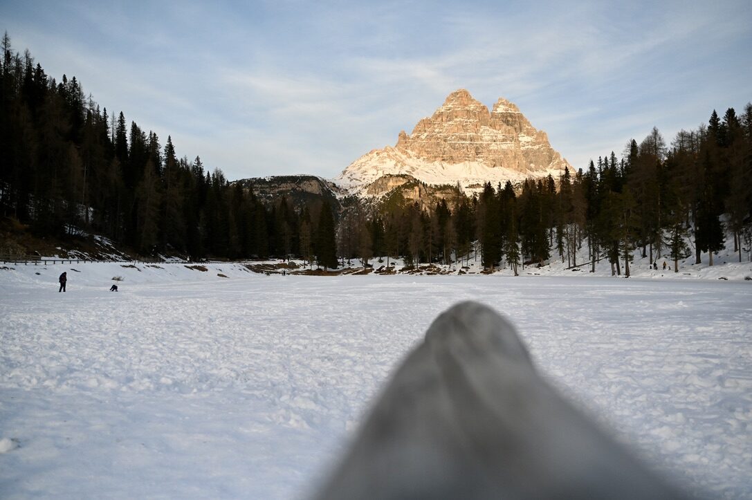 A single peak glowing in the last sun beyond a snowy frozen lake
