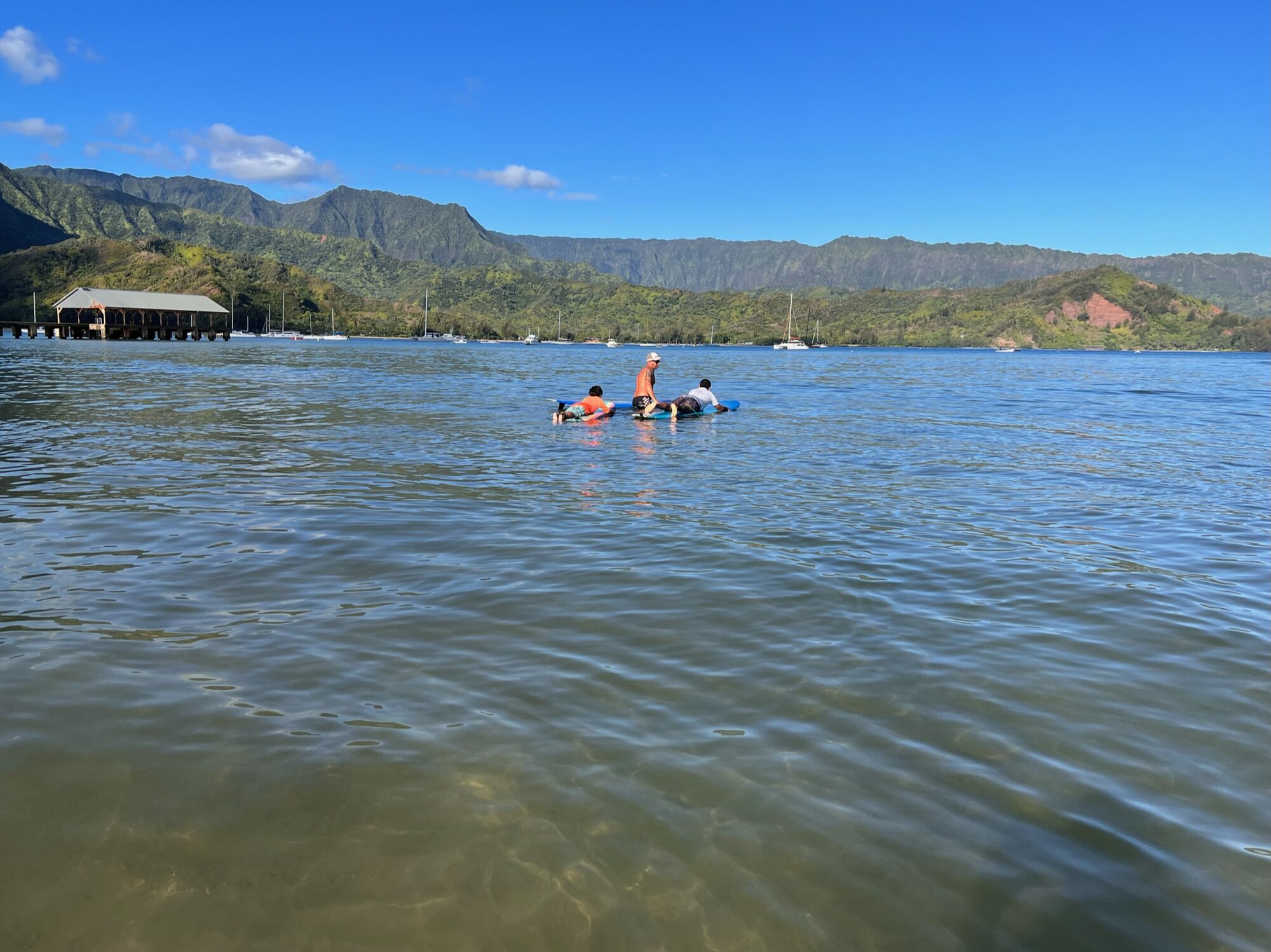 A surf lesson in the calm water of Hanalei Bay, below green mountains