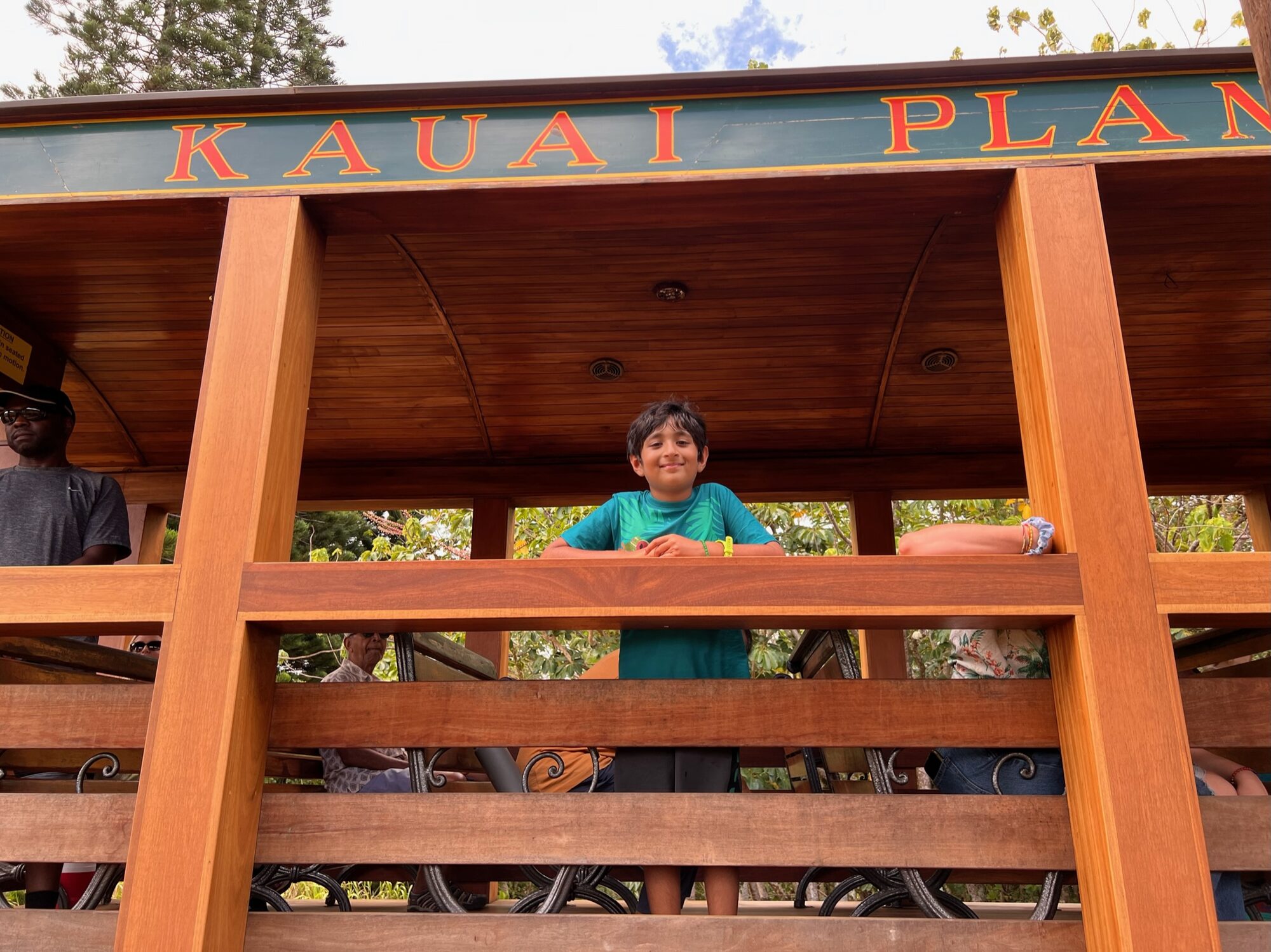 Boy smiling from the open wooden carriage of the Kauai Plantation Railway