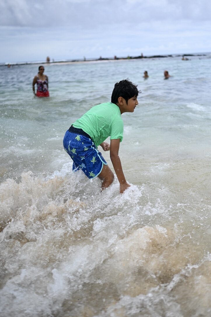 Boy playing in the splashing waves at Poipu Beach