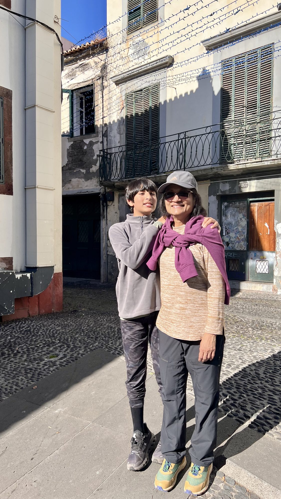 Two of us standing on the cobbled street outside, in front of old buildings with wooden shutters.