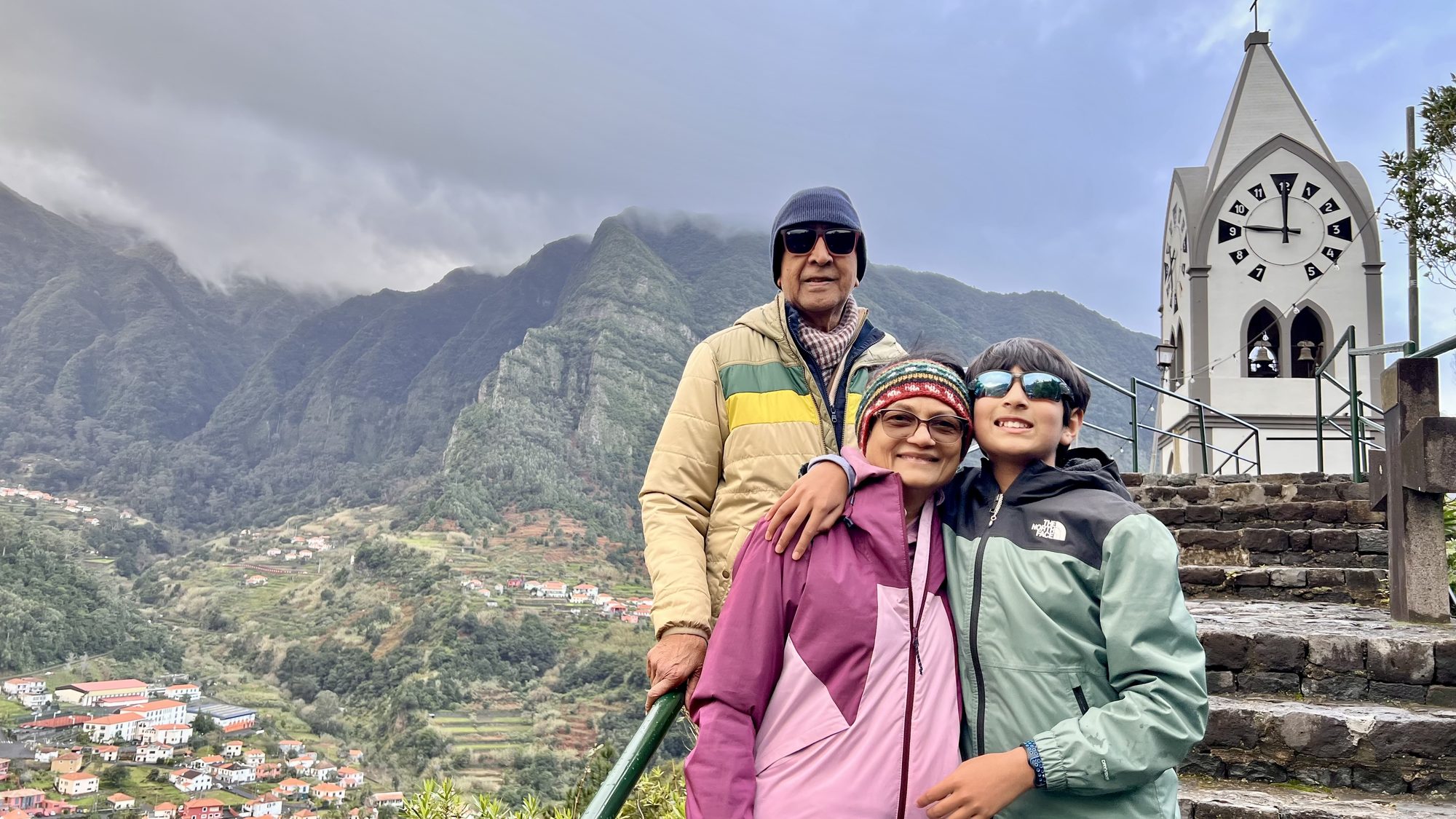 Three of us bundled up in warm jackets at the top of the steps, next to the white chapel’s clock tower, with the valley behind.