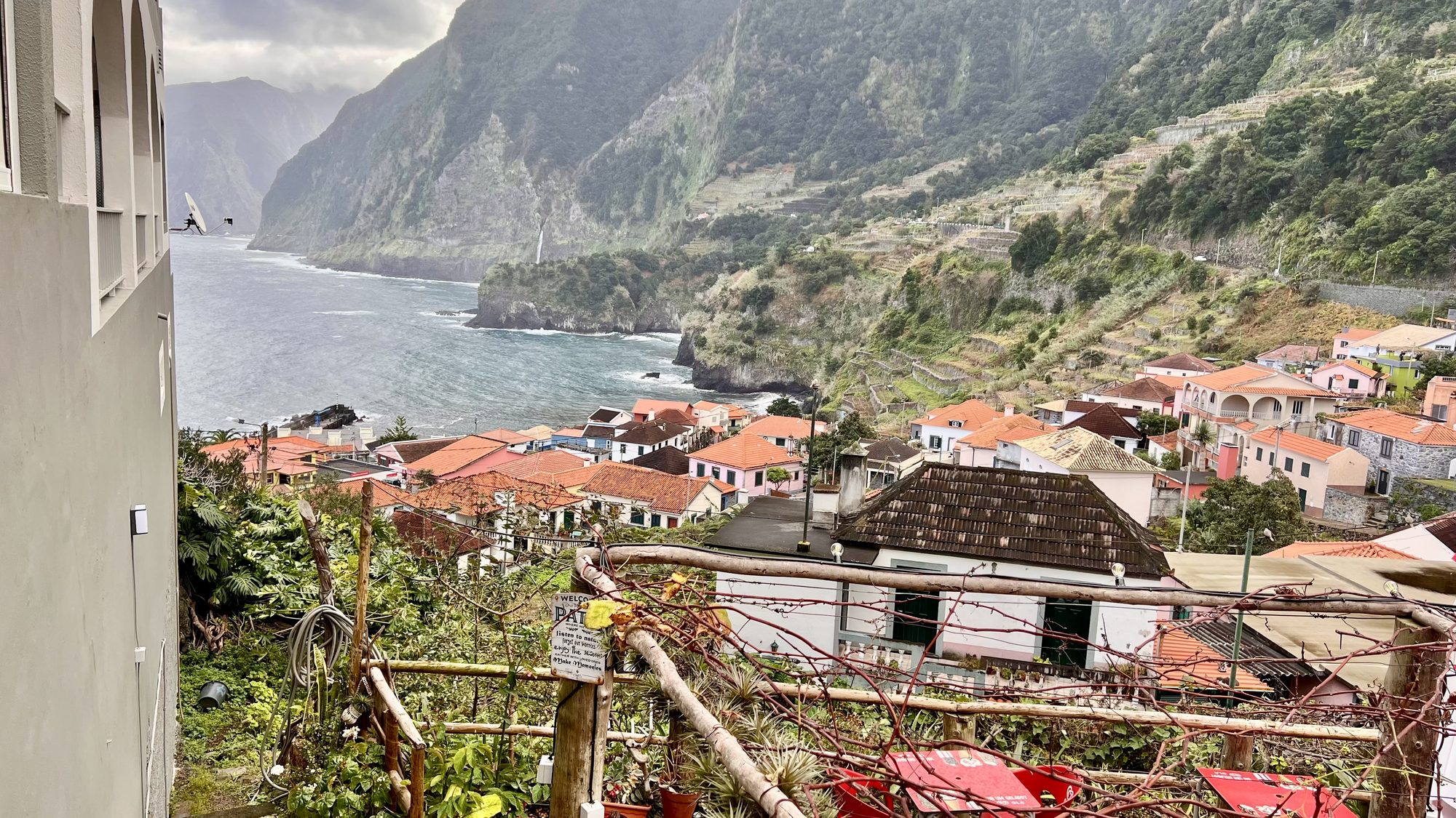 Red-roofed houses of Seixal stepping down to the sea, with steep green cliffs and the coastline beyond.