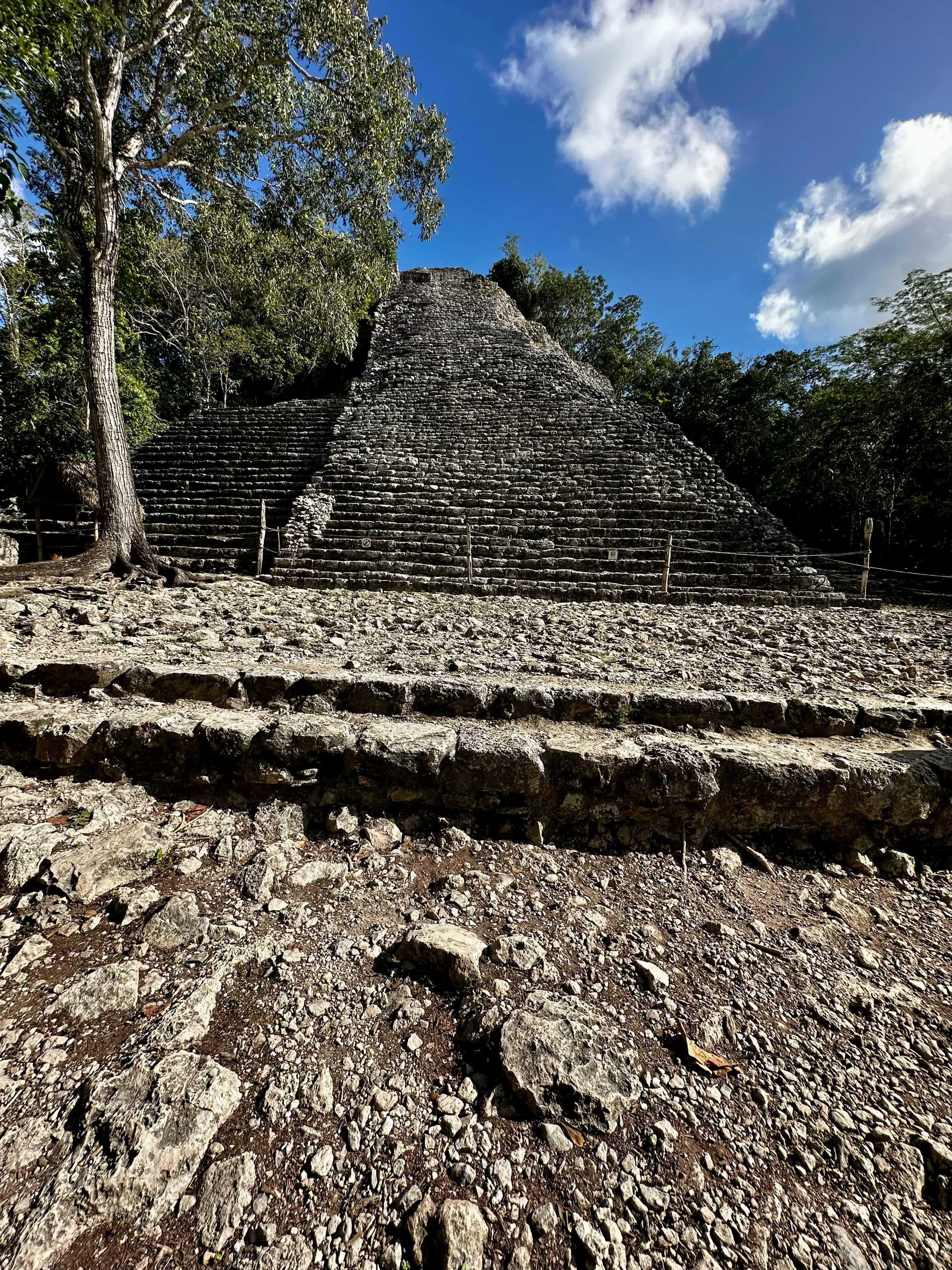 Mayan pyramid in Coba, Mexio with trees surrounding it and pathway with gravel in front of it