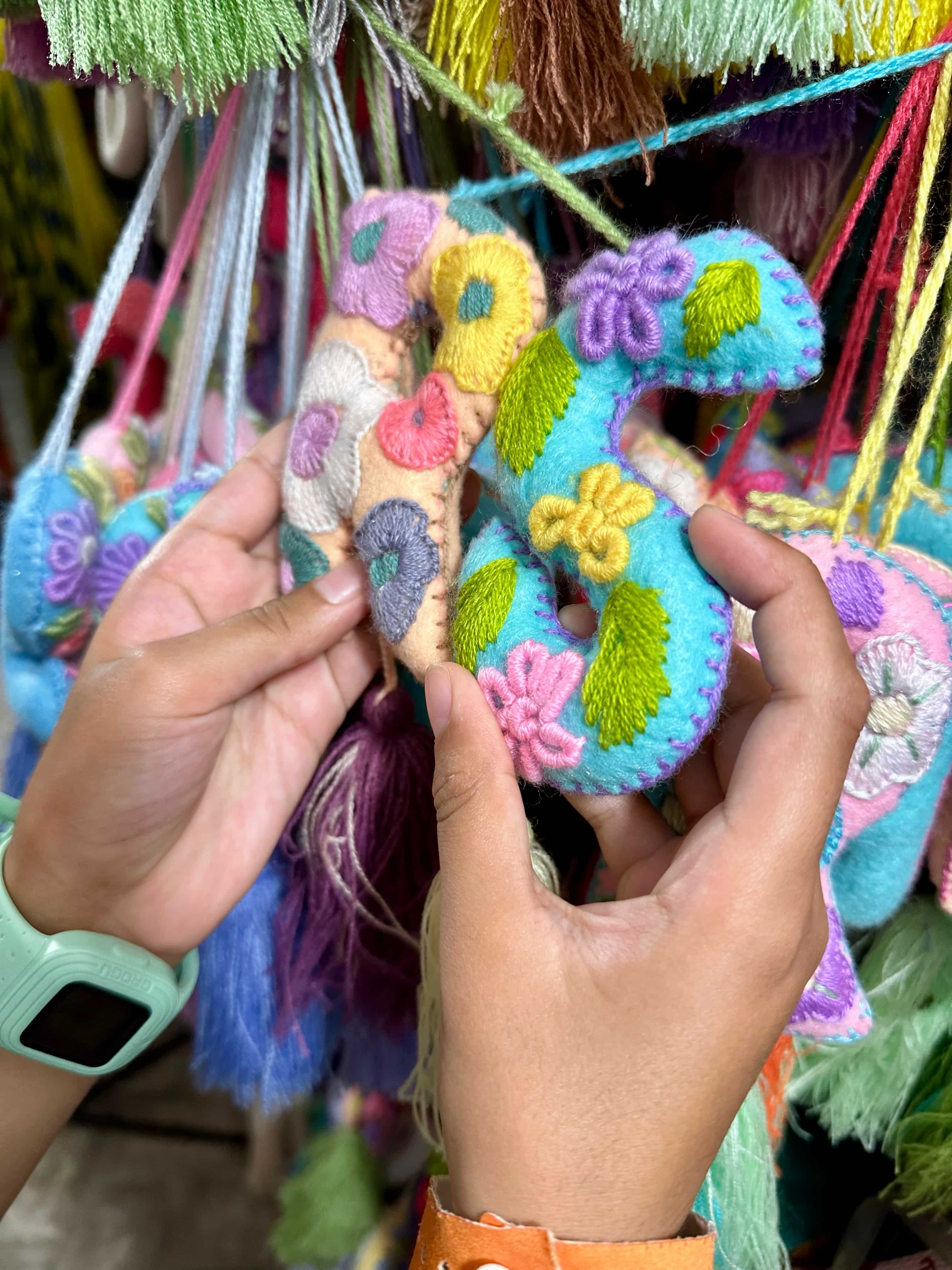 Child's hands holding the letter R and S in Mexican motif made of textile and plush materials