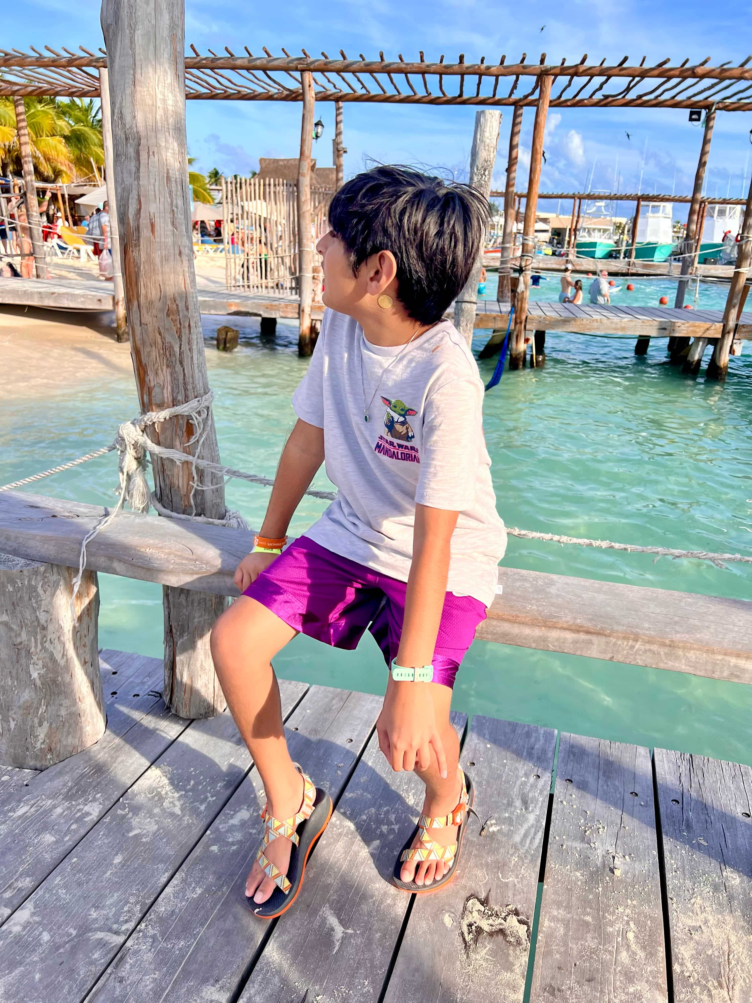 Boy sitting on a sea dock with clear turquoise waters