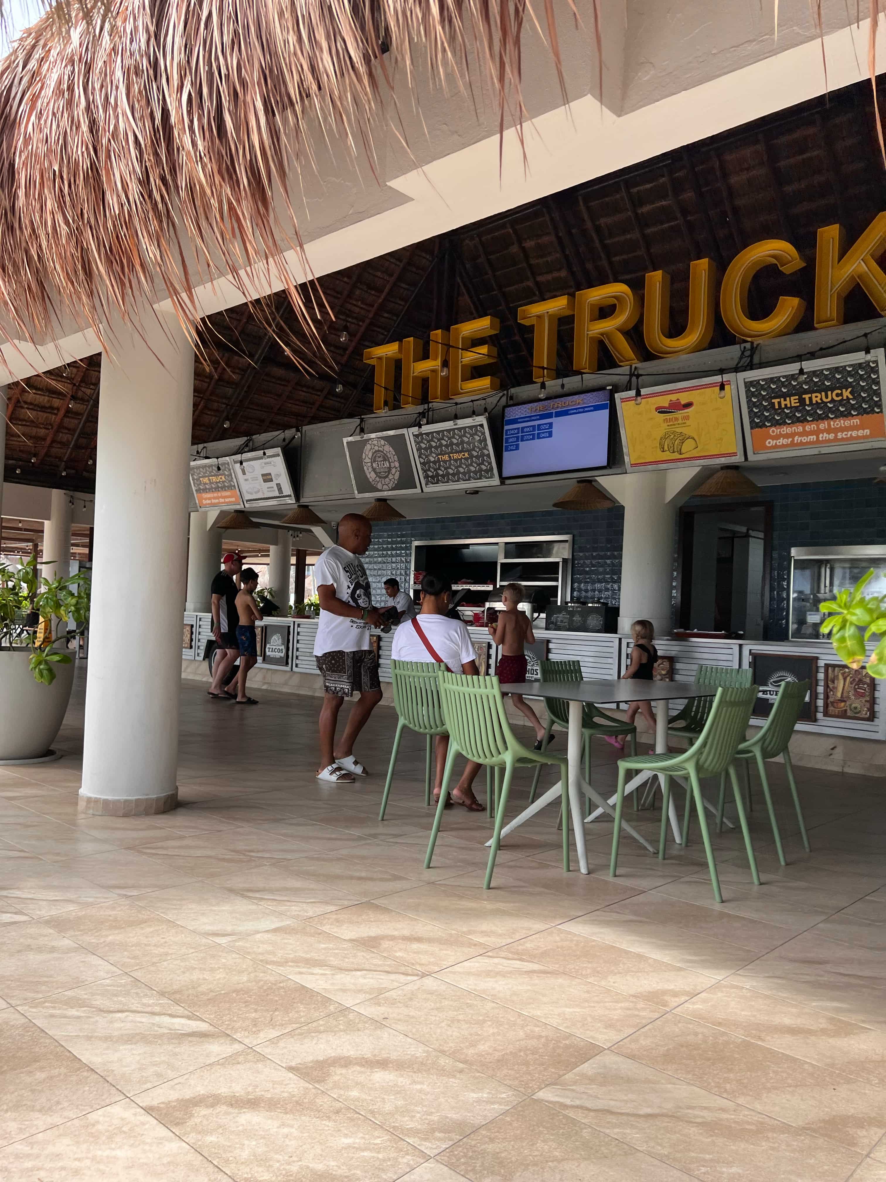 Open beach side restaurant with chairs and tables with people walking around