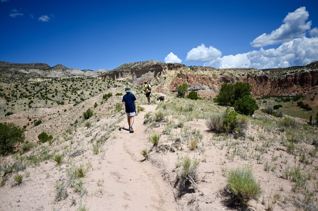 Man and boy hiking a sandy trail through the desert at Ghost Ranch