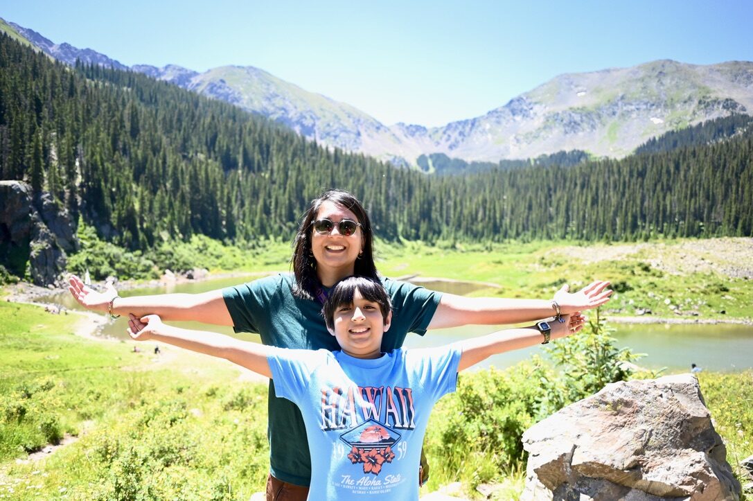 Woman and boy with arms stretched wide in front of Williams Lake and the mountains