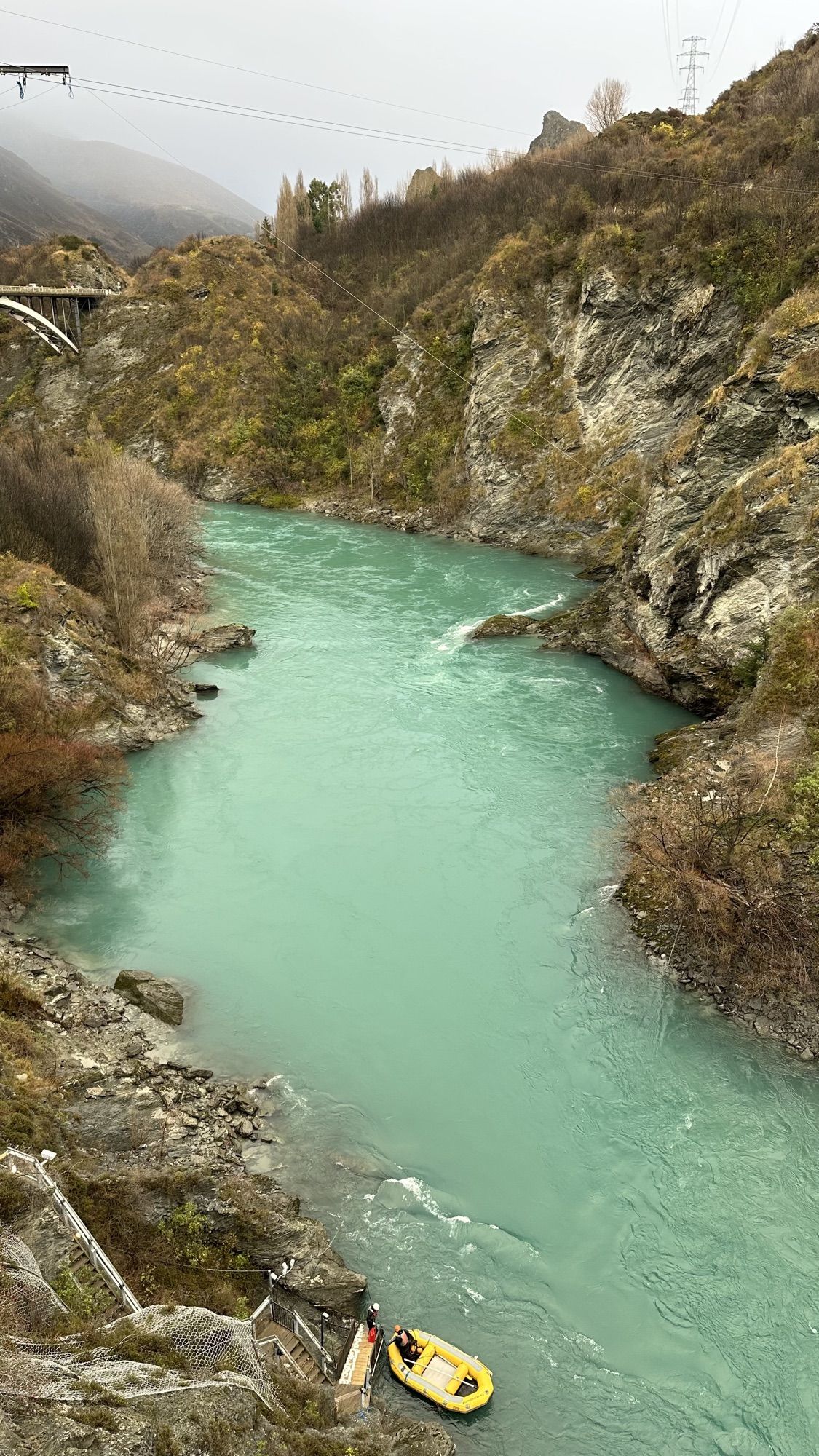 The turquoise Kawarau River flowing through a rocky gorge, with a yellow raft below.