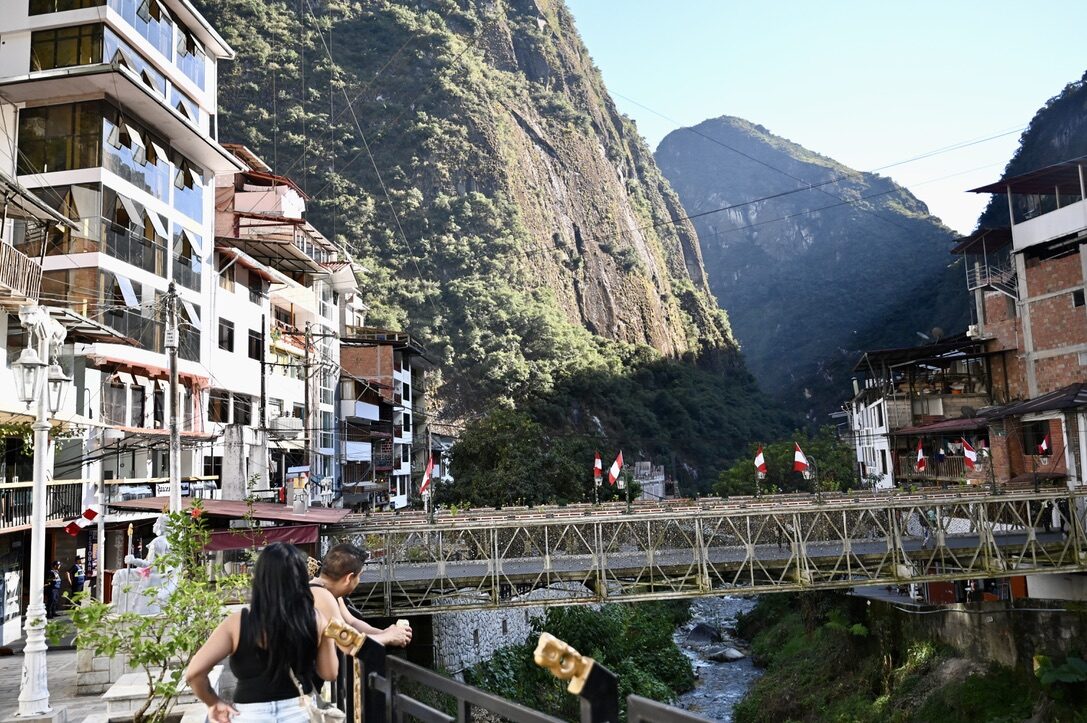 The river through Aguas Calientes, with a bridge and hotels below the mountains