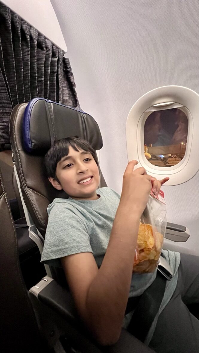 Boy smiling in an airplane seat by the window