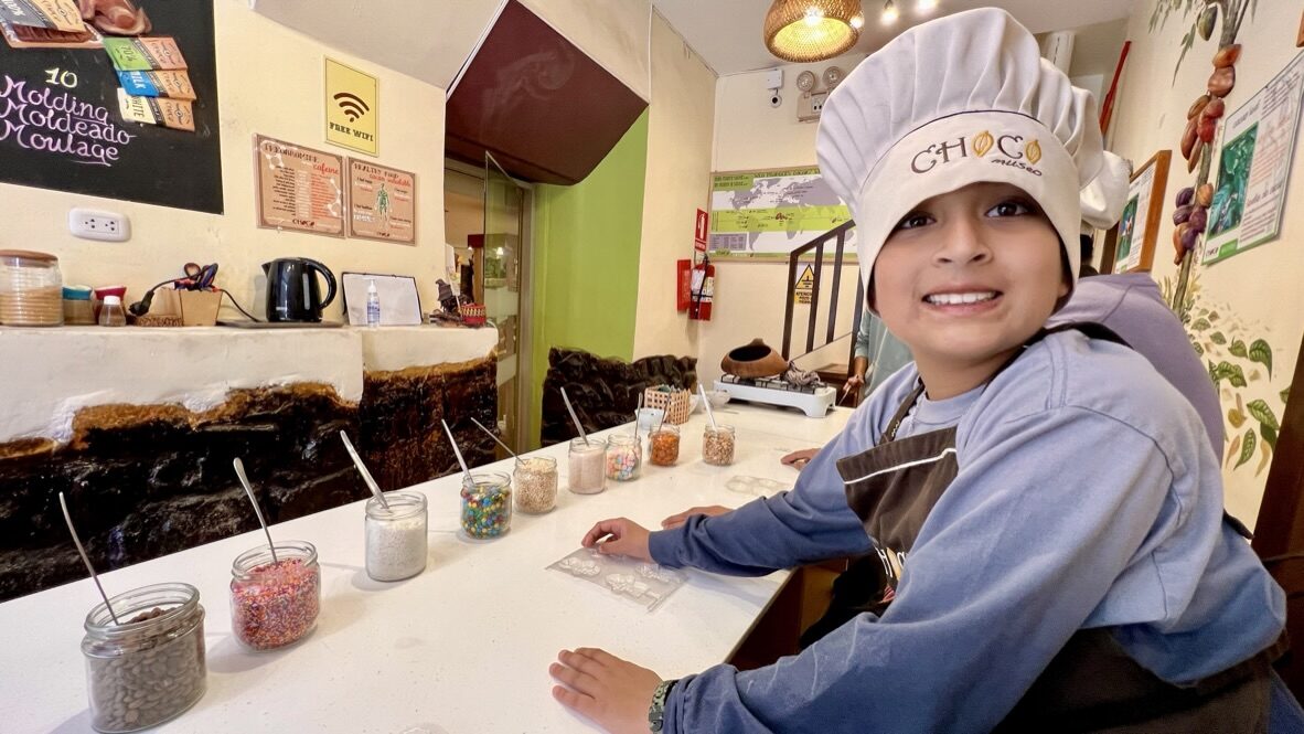 Boy in a chef’s hat smiling at the chocolate workshop counter